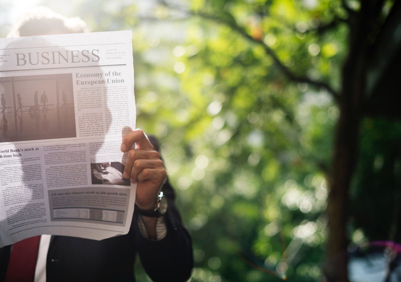 a businessman reading a newspaper in a park, businessman with a newspaper 4k