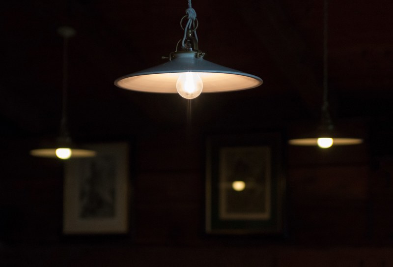 industrial lamps hang from a ceiling in a living room, warm light in the dining room 4k