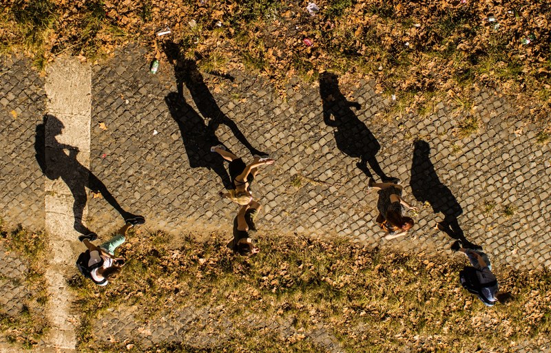 a drone view of people and their shadows walking on a cobblestone pathway, people and their shadows 4k