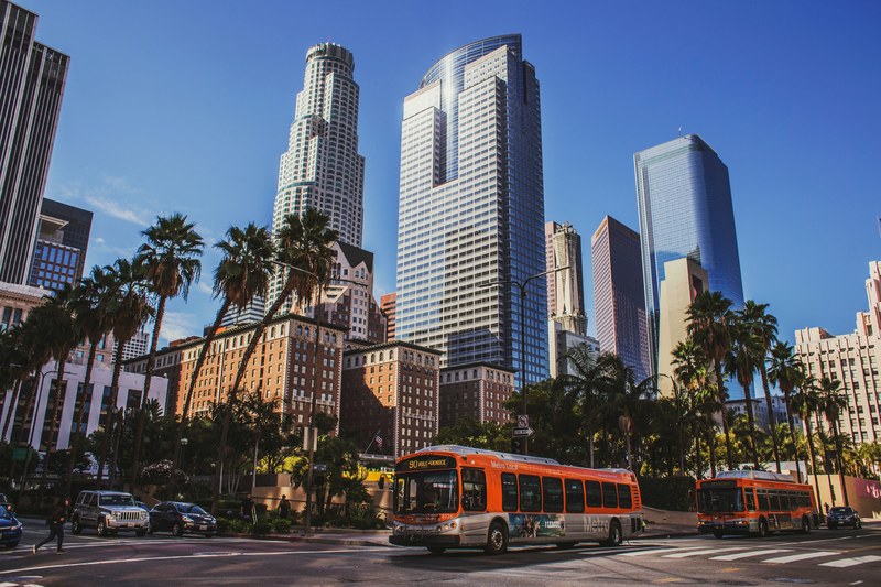 sunny urban downtown road in business district with buses skyscrapers and palm trees, sunny business district roads 4k