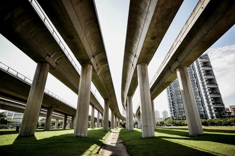a singapore freeway and train overpass with skyscraper in the background, urban beauty 4k