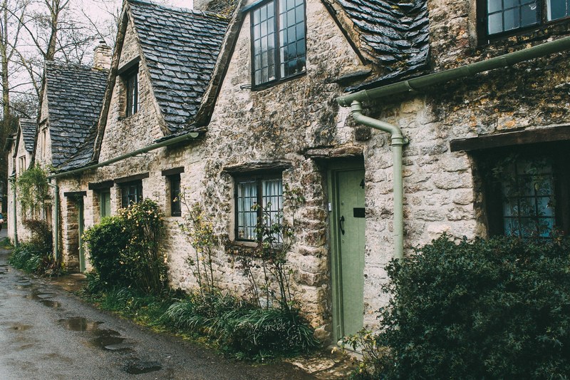 a cottage building with a tile roof and plants in front of it in an old street, building in an old street_ 4k