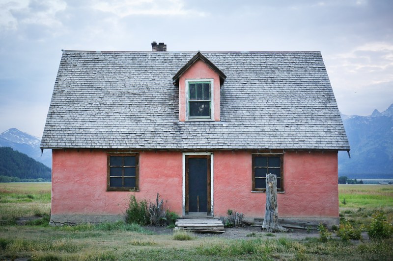 small pink house with 3 windows in a grassy field with mountains in the background, small pink cottage 4k