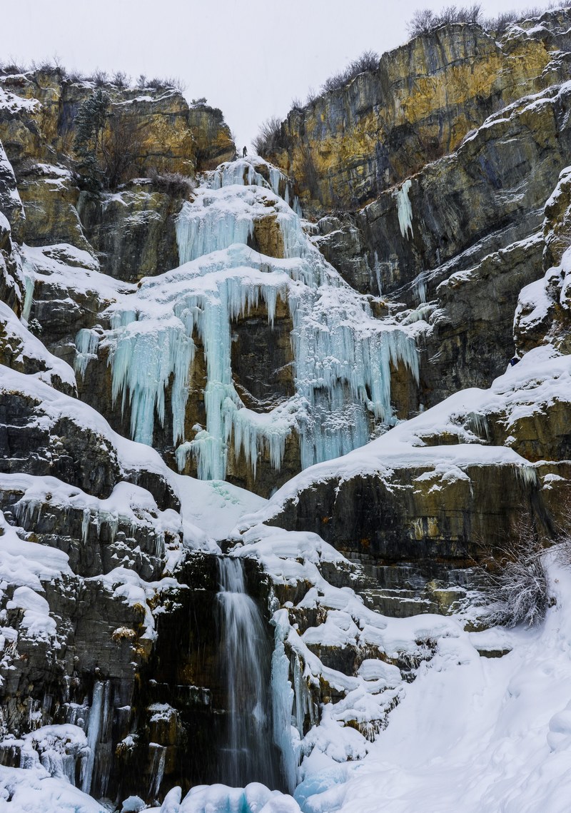 frozen icy waterfall cascades down rocky cliff, frozen 4k