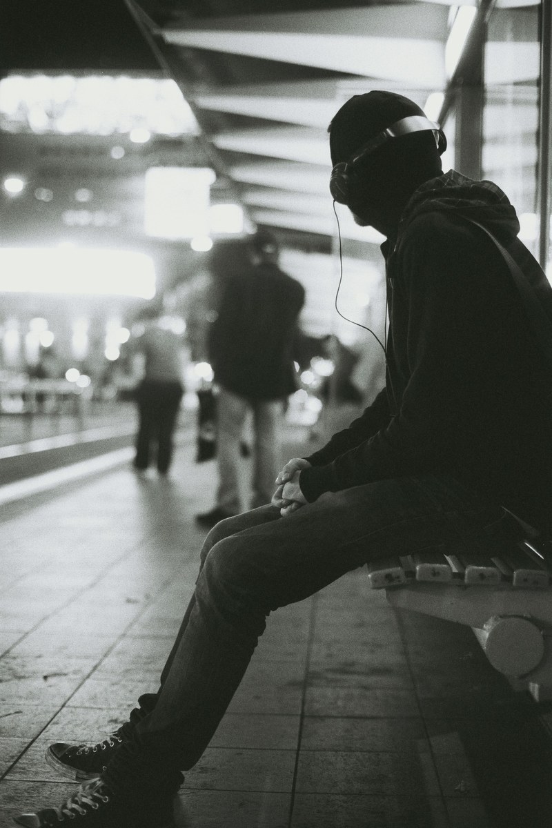 a man is waiting at the bus stop wearing headphones in melbourne, _tram boy 4k