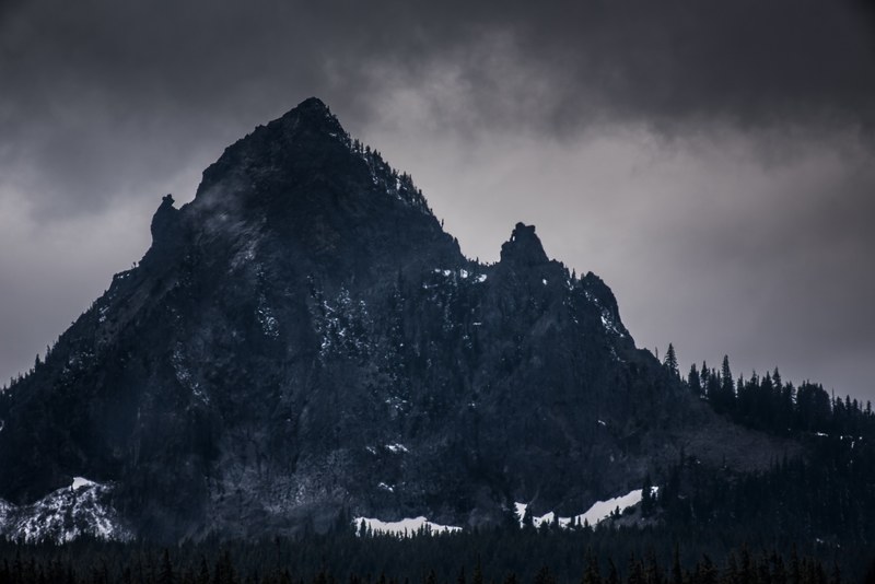 a bleak shot of a free standing mountain with woods at its base, bleak mountain 4k