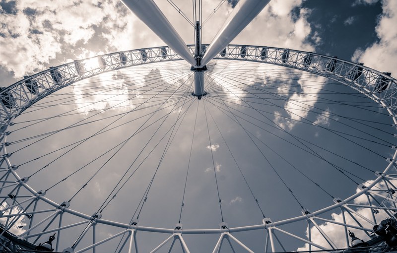 a ferris wheel seen against a blue sky with fluffy clouds, watching the sunset over the river thames 4k