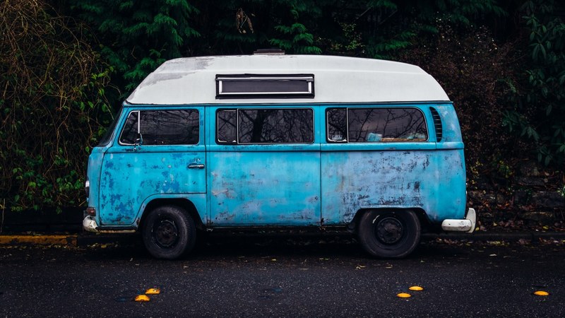 an old blue camper van with a white top parked on the side of the road, old hippie bus 4k