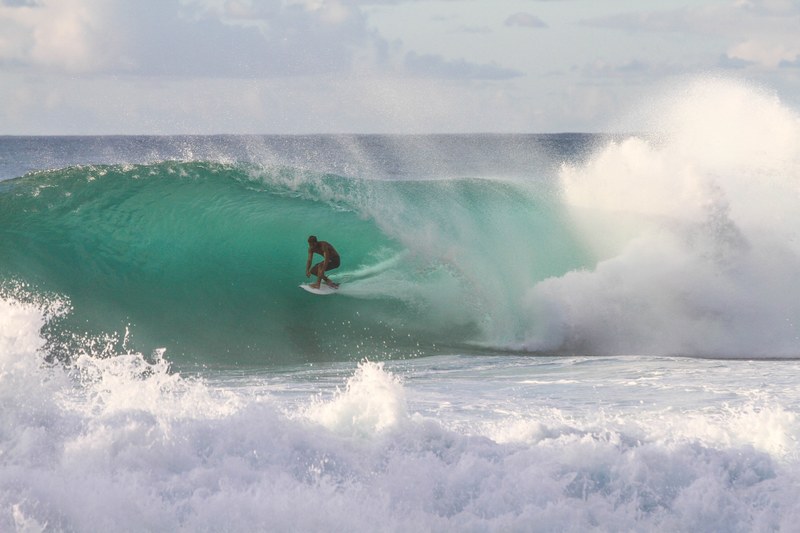 a surfer riding a large wave in the foaming sea at north shore, surfer in the foaming water 4k