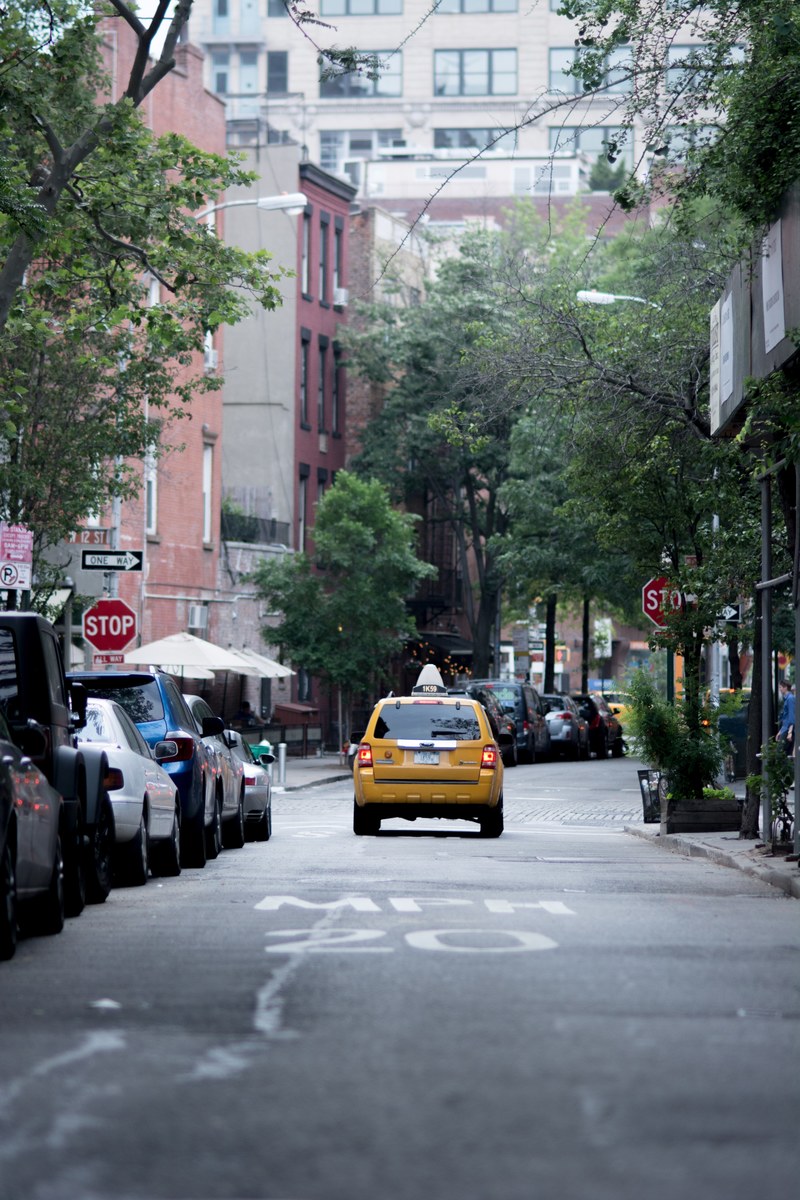 a yellow taxi cab in front of a stop sign on a new york side street, yellow taxi in the west village 4k