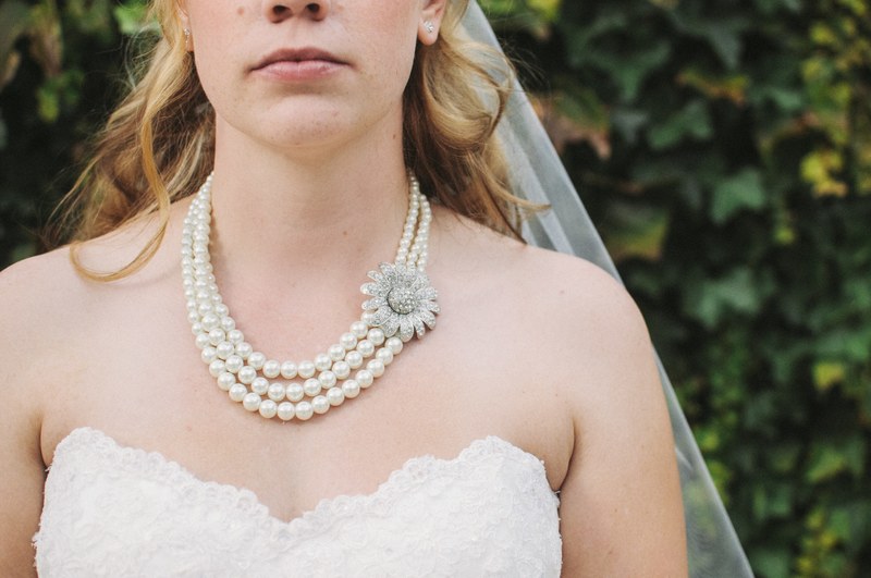 a close up of a brides chest showing her wedding dress veil and pearl necklace, london bride with pearls 4k