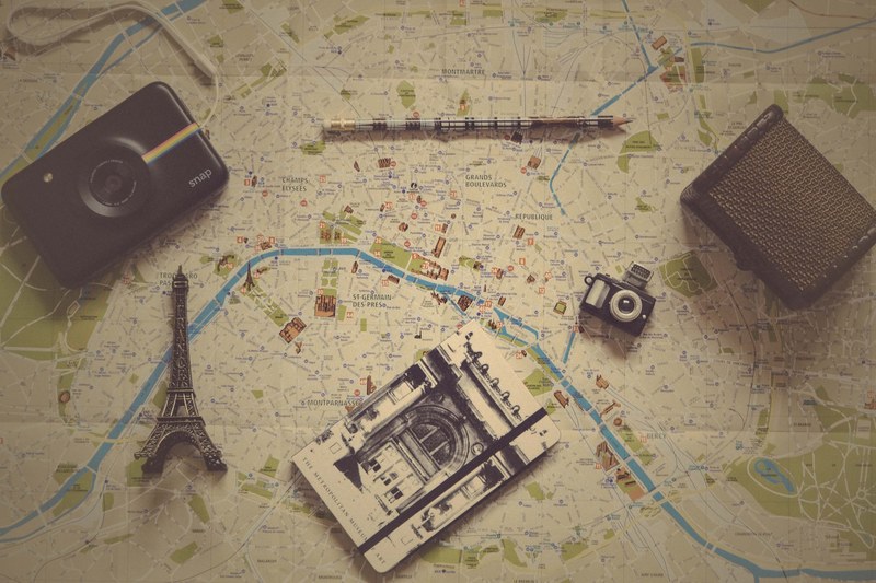 vintage photo of small trinkets a camera and a journal on a map, map of paris 4k