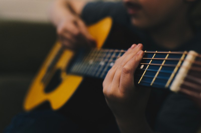 a fuzzy shot of a man playing an acoustic guitar, early guitar days 4k