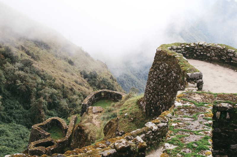 rocky inca ruins covered in moss on a misty mountain, mountainside ruins 4k