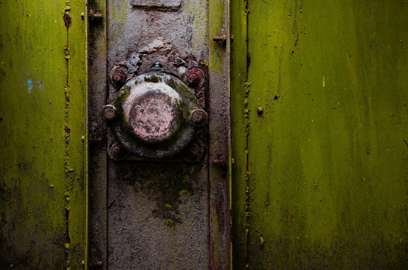 a close up of a rusty metal knob on a green strongbox, in to the green 4k