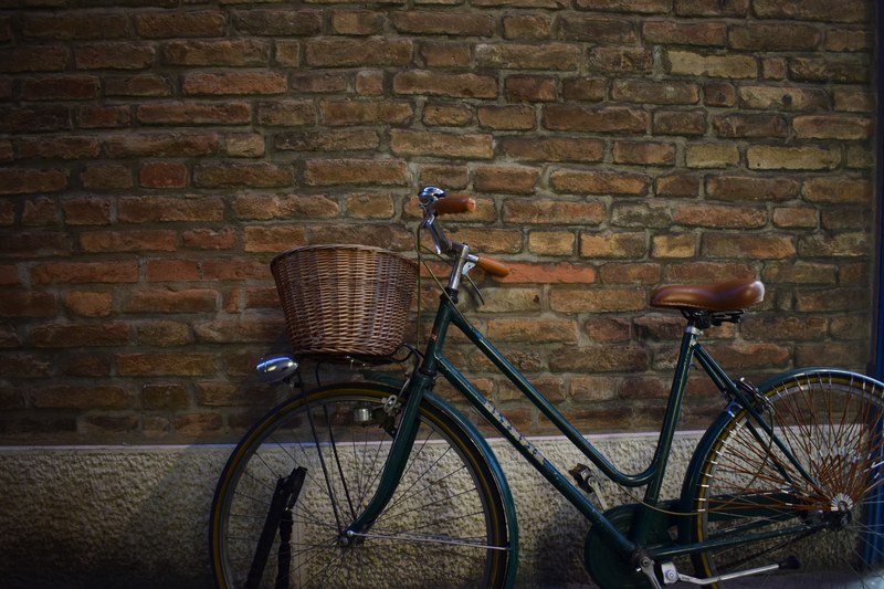 a bicycle with a wicker basket parked next to a brick wall, the wall 4k