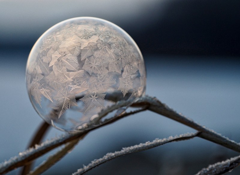 a macro frozen bubble with snowflake and crystal formations inside, frozen snowflake bubble 4k
