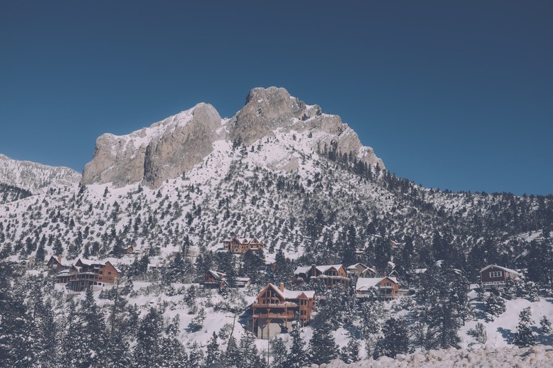 cabins among the forest of a snowy mountain landscape, mountain resorts on a slope 4k