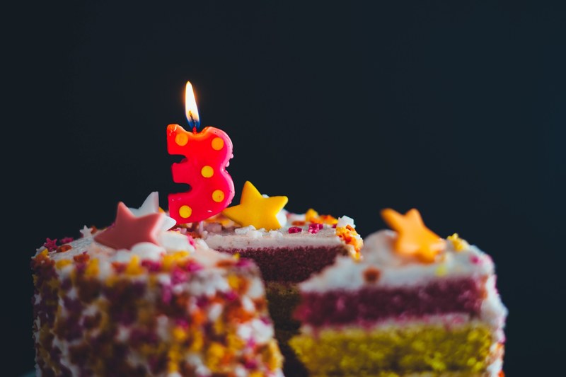 a close up macro shot of a sliced birthday cake with a number 3 candle burning on top, 3rd birthday cake 4k