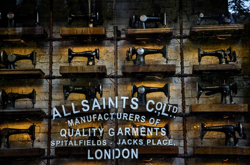 a number of singer sewing machines on shelves behind a store window, sewing machines in chicago 4k