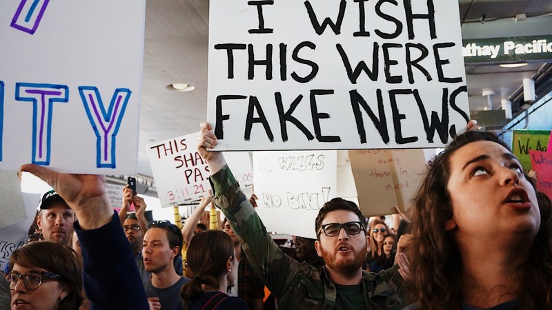 protesters are holding various signs with different messages during a rally at lax airport, _fake news 4k