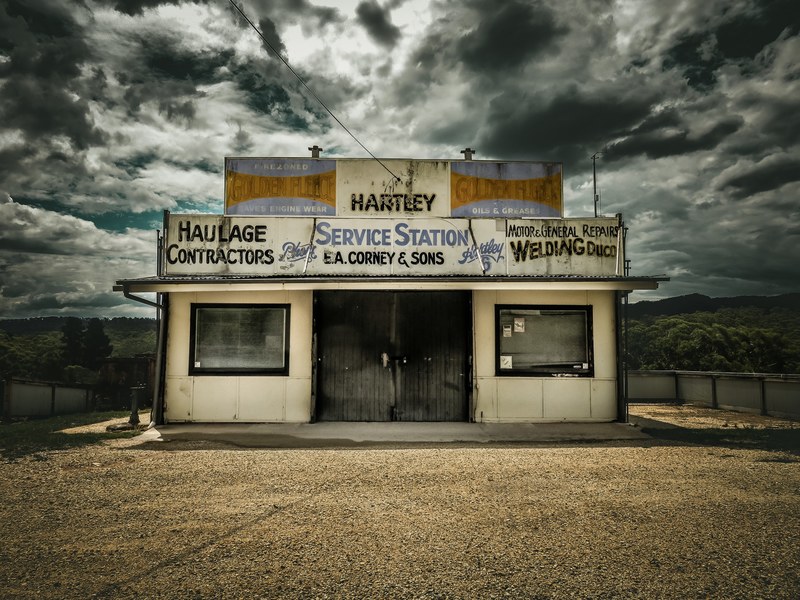 a small car service station at the roadside under a cloudy sky, small service station 4k