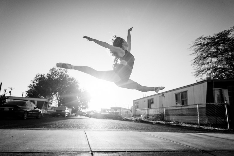 black and white shot of a female ballet dancer in a split in midair as sun shines in the distance, leap 4k