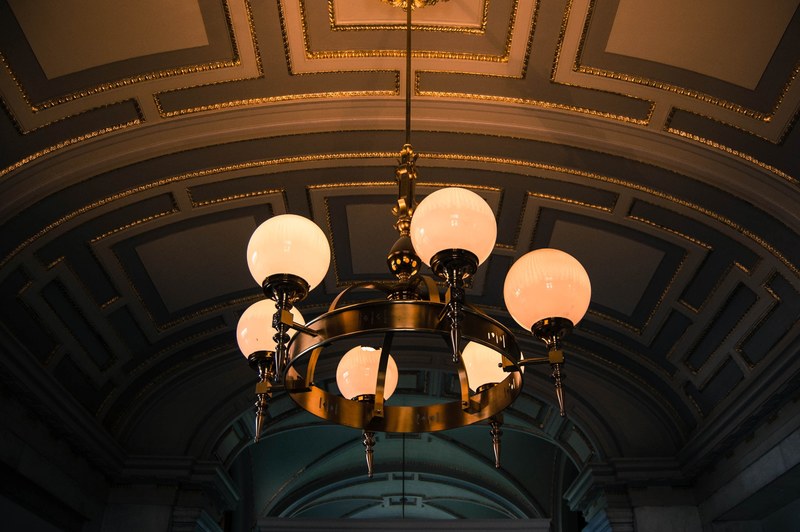 incandescent globe bulbs on a gold chandelier hanging from an ornate ceiling, elegant chandelier 4k