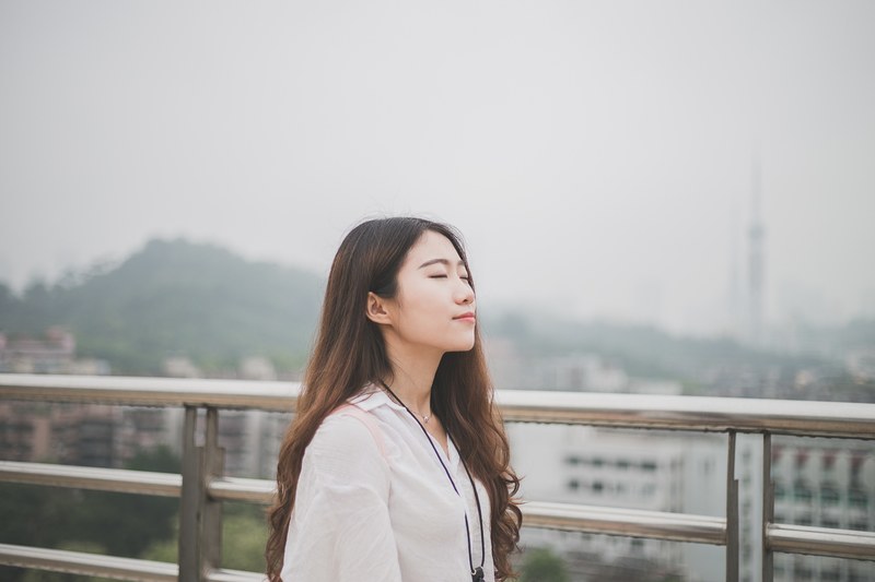 a young woman with her eyes closed with buildings in the background, _woman with eyes closed 4k