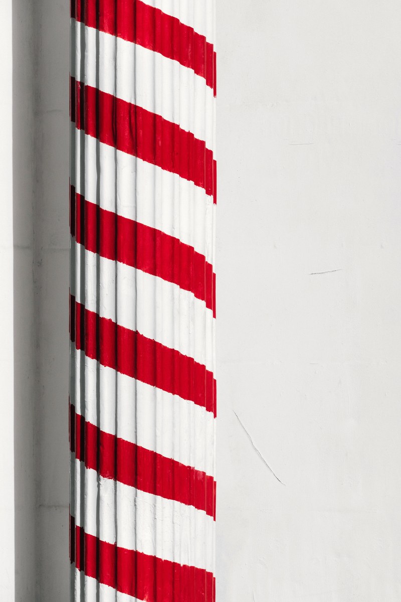a greek column painted in red in front of a barber 4k