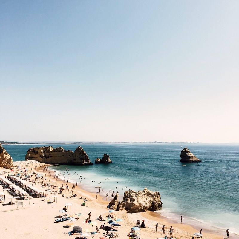 crowded sand beach with rocks on a sunny day in lagos distrito de faro portugal, see you on the seashore 4k