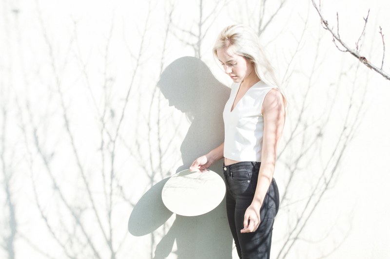 woman in overexposed light holidng a circle mirror, light reflections 4k