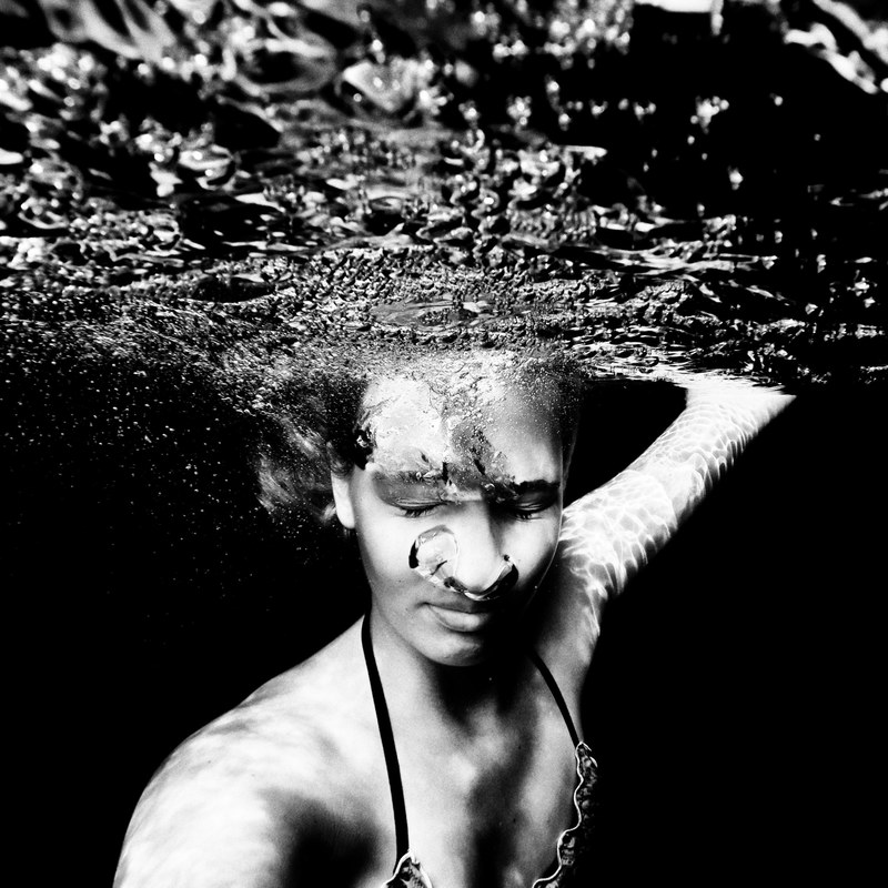 black and white shot of woman swimming underwater blowing bubbles lago di chamol, underwater 4k