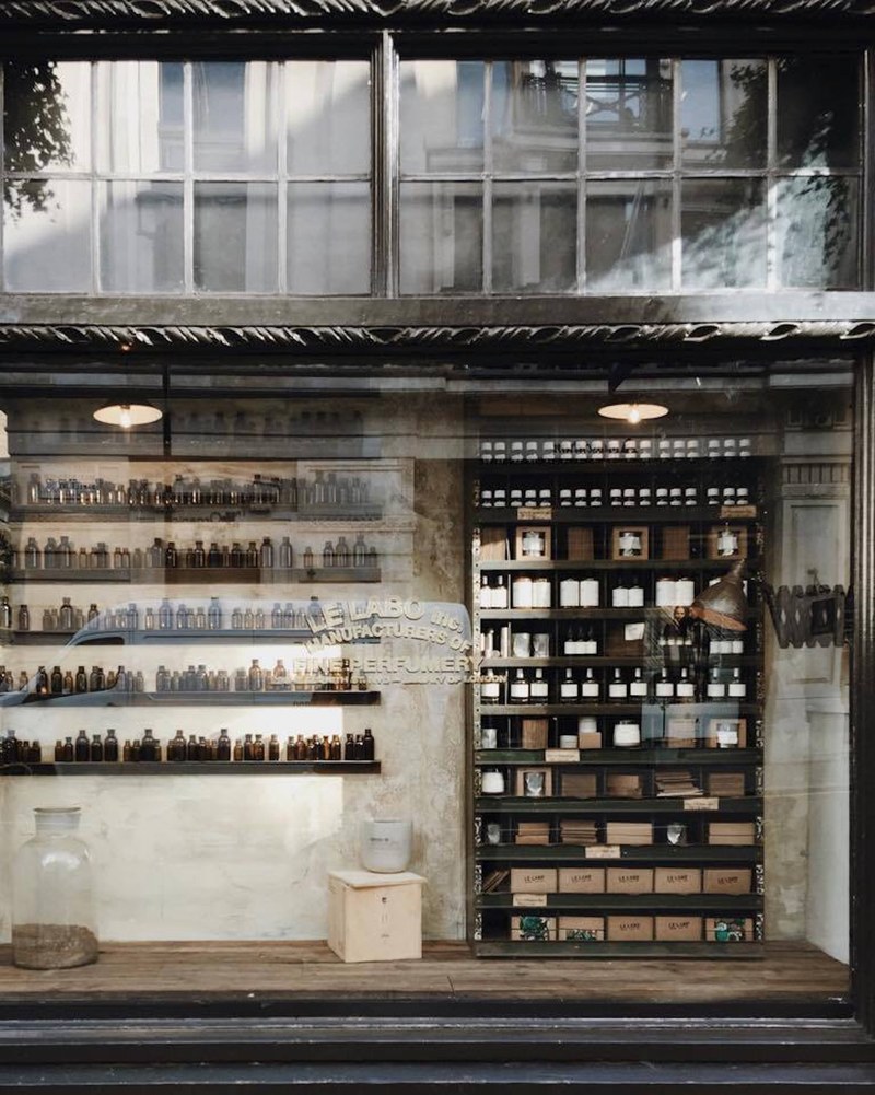the front view of a shop with glass windows containing glass bottles and a shelf in london, old shops containing bottles_ 4k