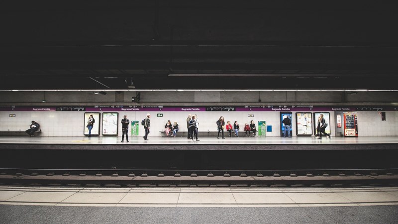 diverse group of people wait for the train to arrive at the station, sagrada familia metro 4k