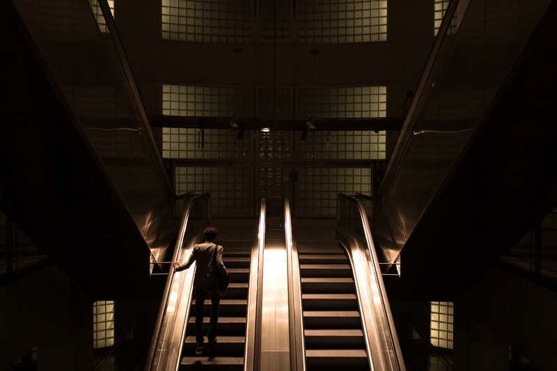 a shadowy shot of a man riding up a pair of escalators in the subway, paris 2013_ 4k