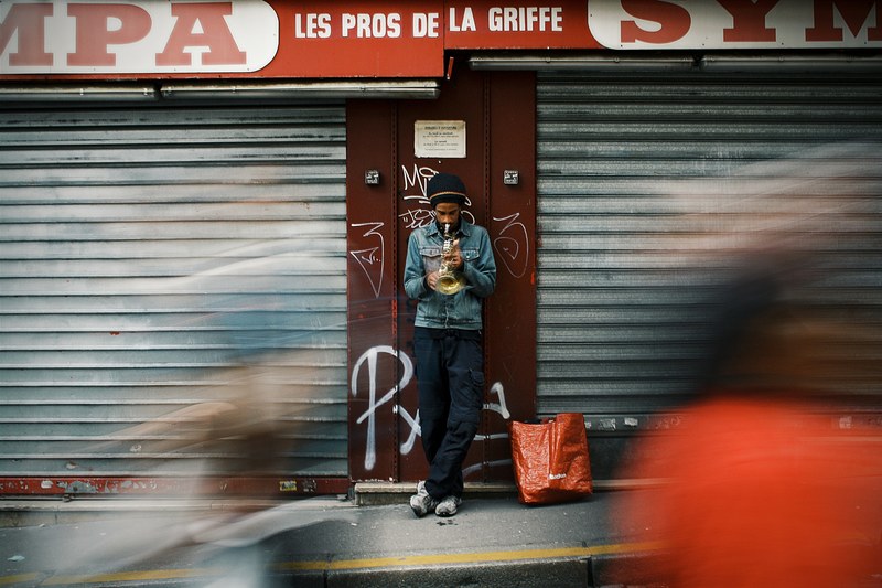 a man playing the trumpet outside a store in paris with blurred people walking by, so what 4k