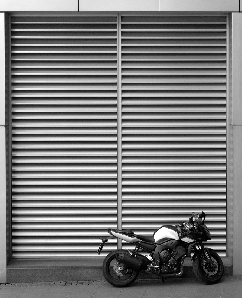 black and white shot of motorbike parked in front of storefront shutters, motorbike with store shutters 4k