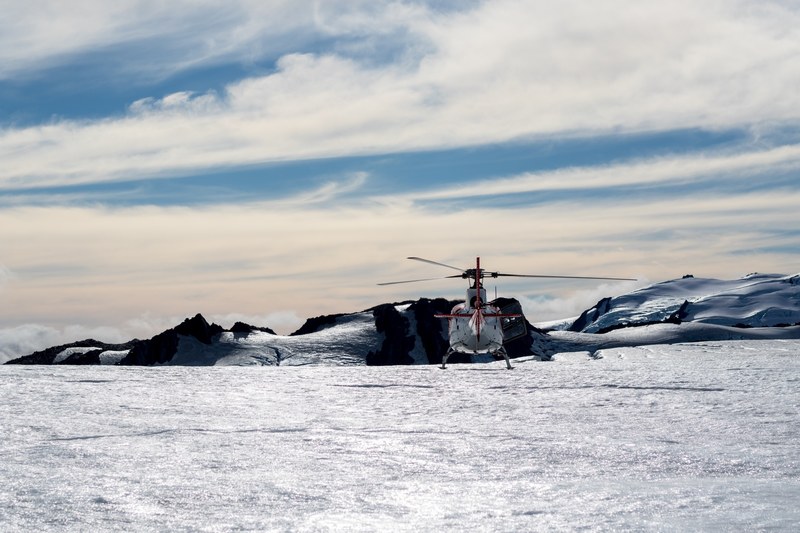 a helicopter sitting in a field of snow at fox glacier in new zealand, helicopter out in snow 4k