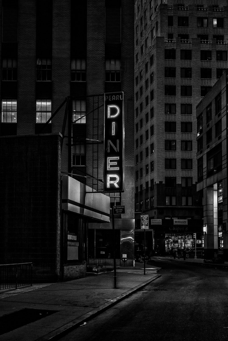 black and white night shot of diner sign surrounded by city buildings in financial district, diner sign financial district 4k