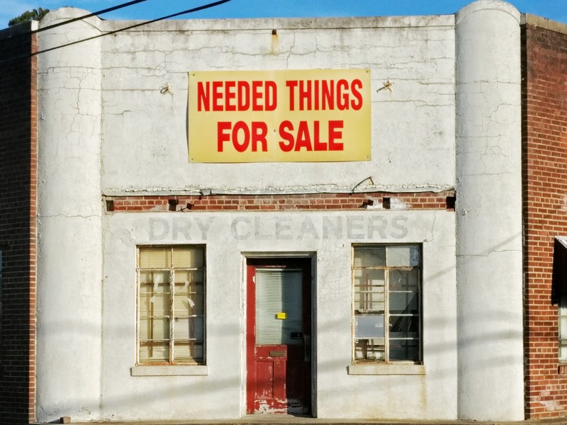 the storefront of an old dry cleaners business with a faded sign, old dry cleaners storefront 4k