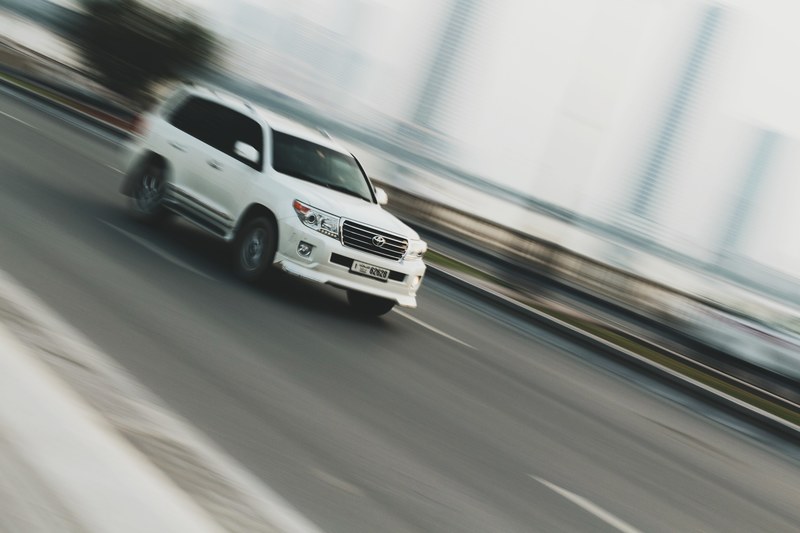 a blurry shot of a white suv driving on a road in al qasba, pride of the highway 4k