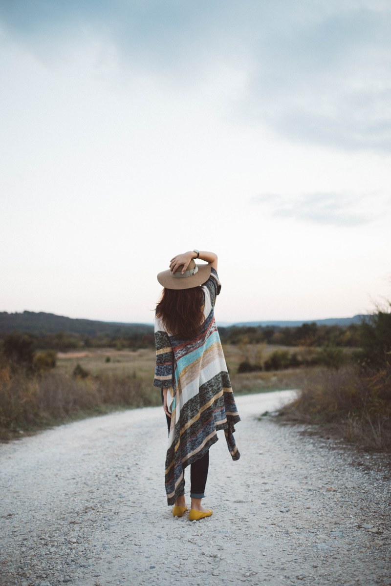 woman in a long striped sweater and hat standing on a deserted road, exploring alone 4k