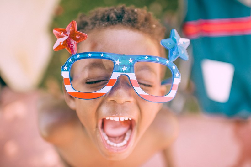 a child making a funny face while wearing goofy american patriotic glasses with plastic stars, san diego 4k