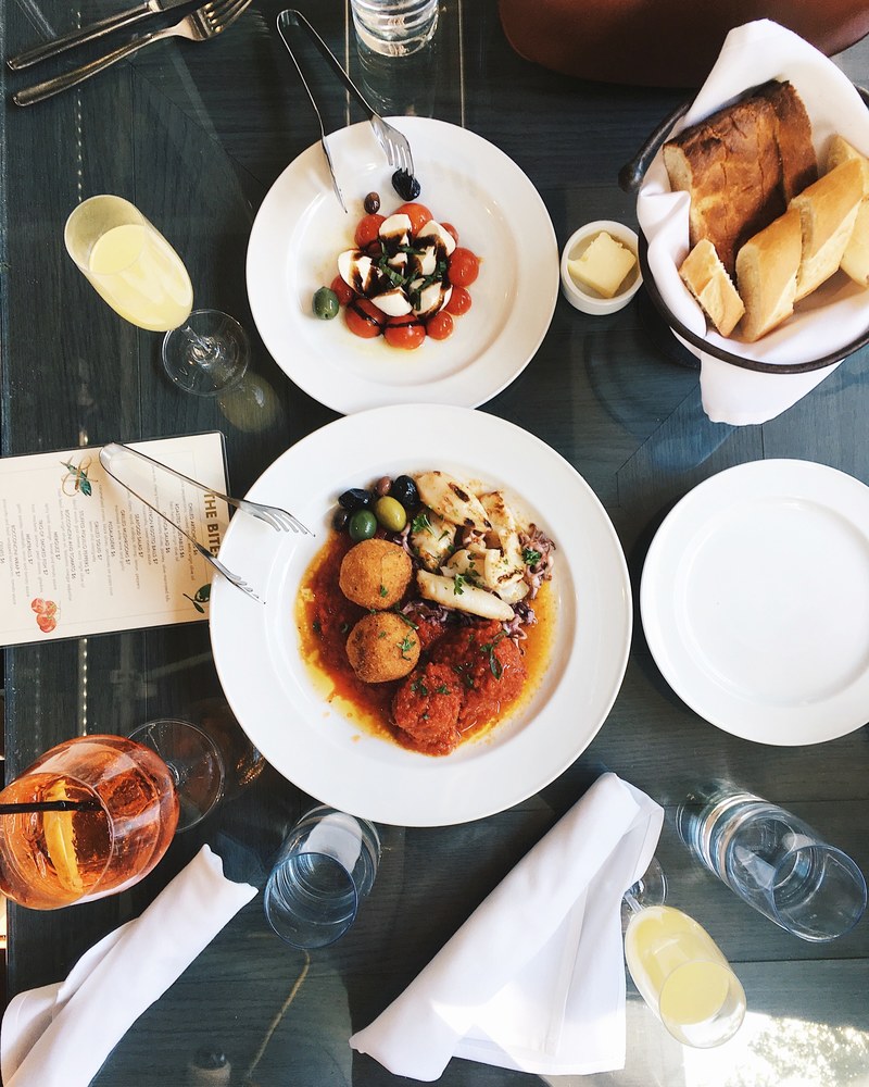 a top down view of a restaurant dining table with a menu drinks and a dish of sliced mozarella and tomatoes, brunch time 4k