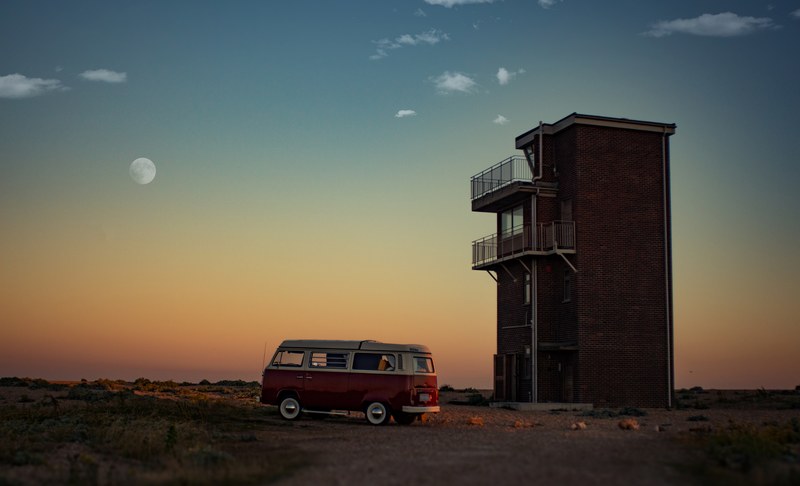 volkswagen campervan parked next to a standalone building in dungeness a dawn or dusk with a faint moon in the orange fading to blue sky, hipster life 4k