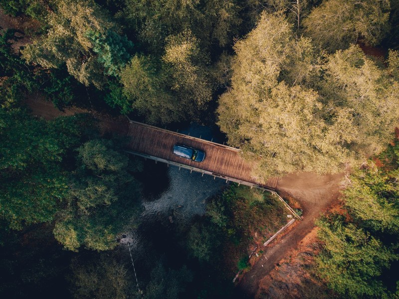 drone aerial view of a car on a wooden bridge in the forest in big sur, big sur road trip 4k