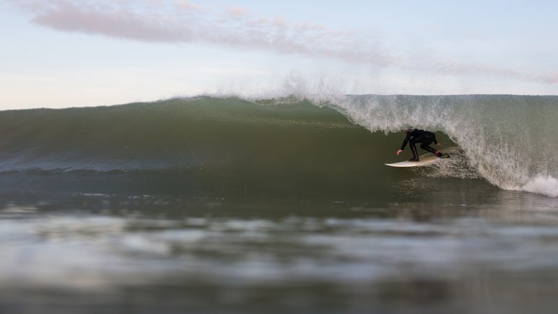 a surfer caught beneath a rolling wave in a gray looking sea at plage du petit bec, surfer under the wave 4k