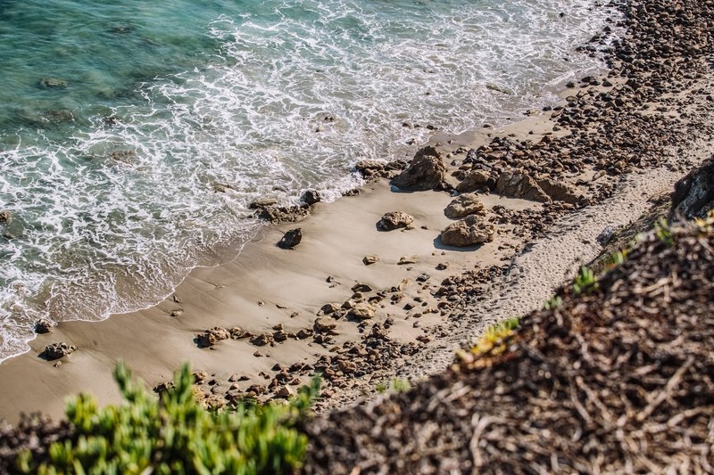 ocean washing on the sandy and rocky coastline viewed from the hill above at point dume state beach, ocean washing on sandy beach 4k