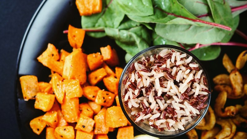 a glass of mixed red and white rice on a plate of salad greens cooked shrimp and diced sweet potatoes, rice and salad 4k